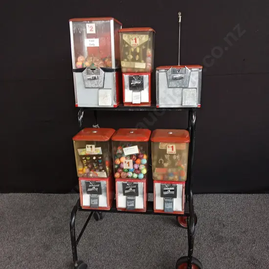 NORTHWESTERN BRAND TOY VENDING MACHINE SET ON STEEL TROLLEY. 6 MACHINES, 1 INCOMPLETE. COIN MECHANISMS BUT NO KEYS,