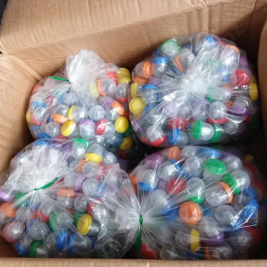 BOX OF PLASTIC CAPSULES FULL OF COSTUME JEWELLERY
