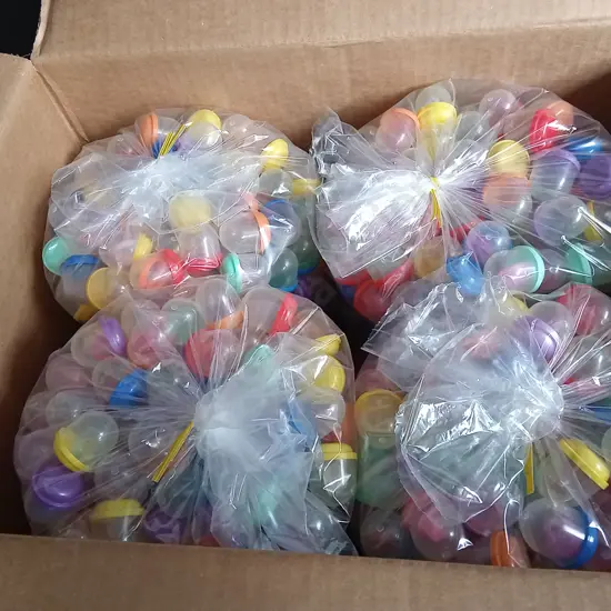 BOX OF PLASTIC CAPSULES FULL OF COSTUME JEWELLERY