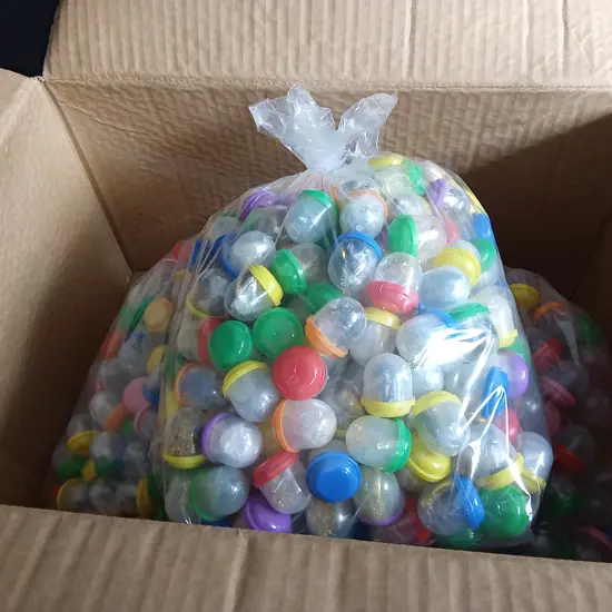 BOX OF PLASTIC CAPSULES FULL OF COSTUME JEWELLERY FOR VENDING MACHINE