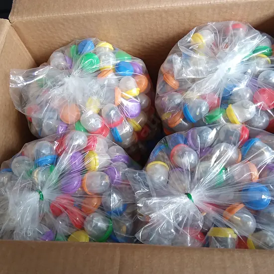BOX OF PLASTIC CAPSULES FULL OF COSTUME JEWELLERY