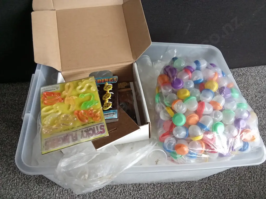 BOX OF PLASTIC CAPSULES FILLED WITH COSTUME JEWELLERY AND OTHER ITEMS Image 1++
