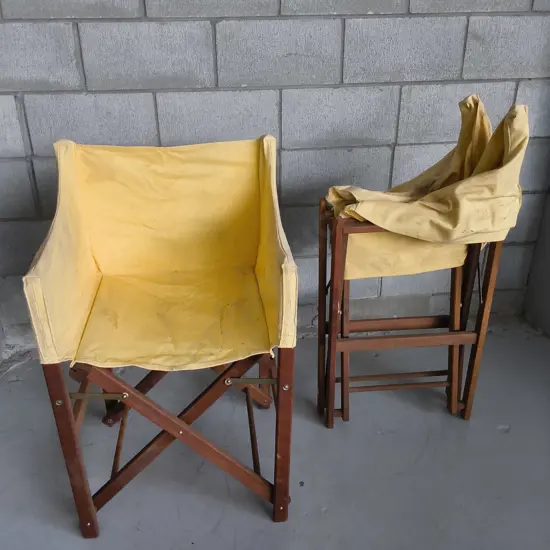 PAIR OF WOODEN FOLDING DIRECTORS CHAIRS WITH YELLOW FABRIC COVERS, DAMAGE PICTURED