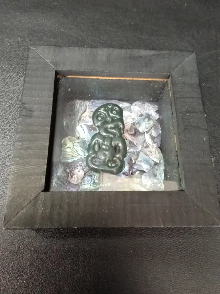 FRAMED SHADOW BOX WITH GREENSTONE HEI-TIKI AND PĀUA 11.5. X 11.5CM Image 1++