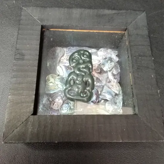 FRAMED SHADOW BOX WITH GREENSTONE HEI-TIKI AND PĀUA 11.5. X 11.5CM